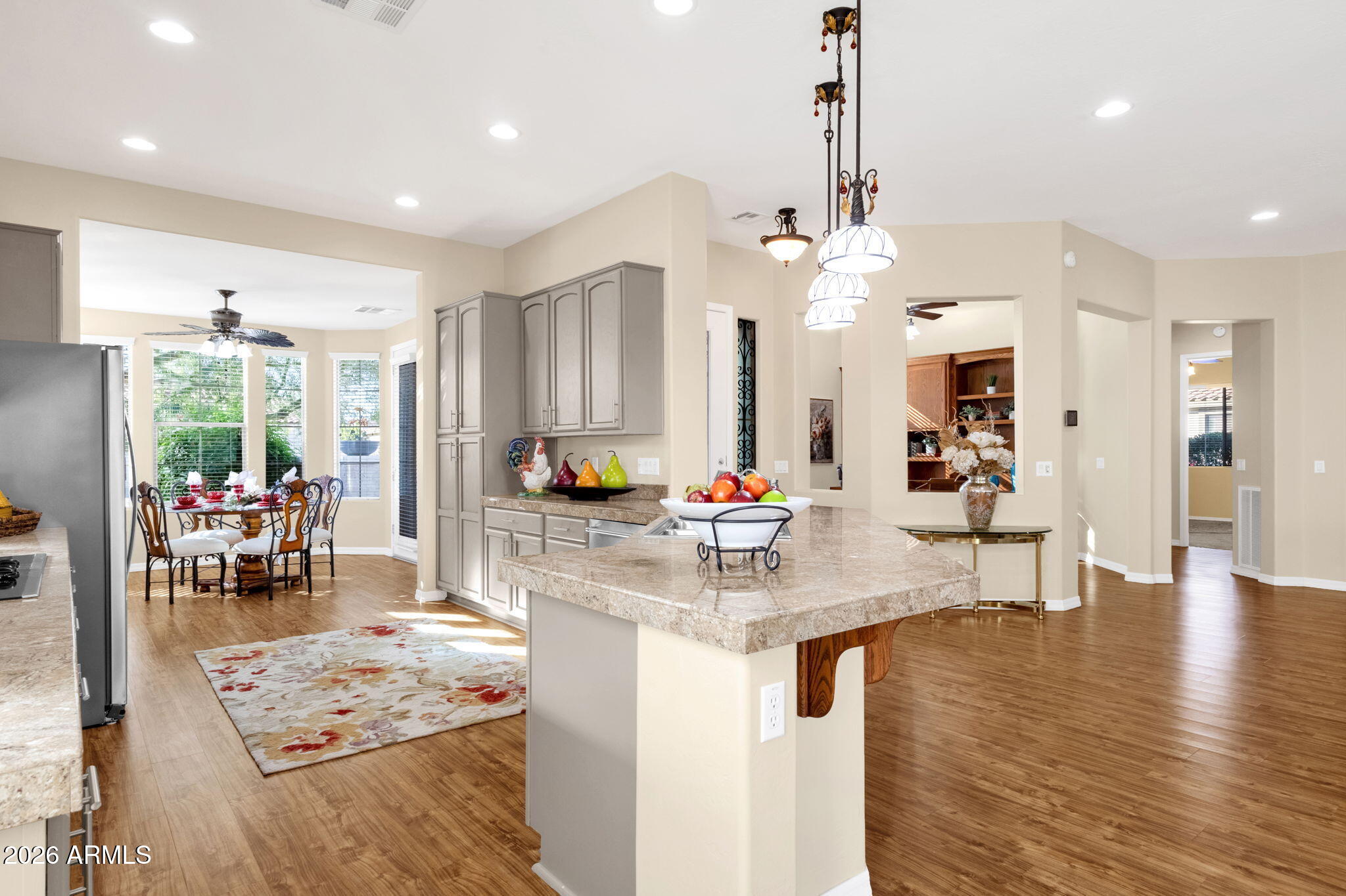 4734 East Indigo Street Gilbert, AZ 85298 - Photo 14 of 32 a kitchen with stainless steel appliances kitchen island granite countertop a sink dishwasher a stove and a dining table with wooden floor