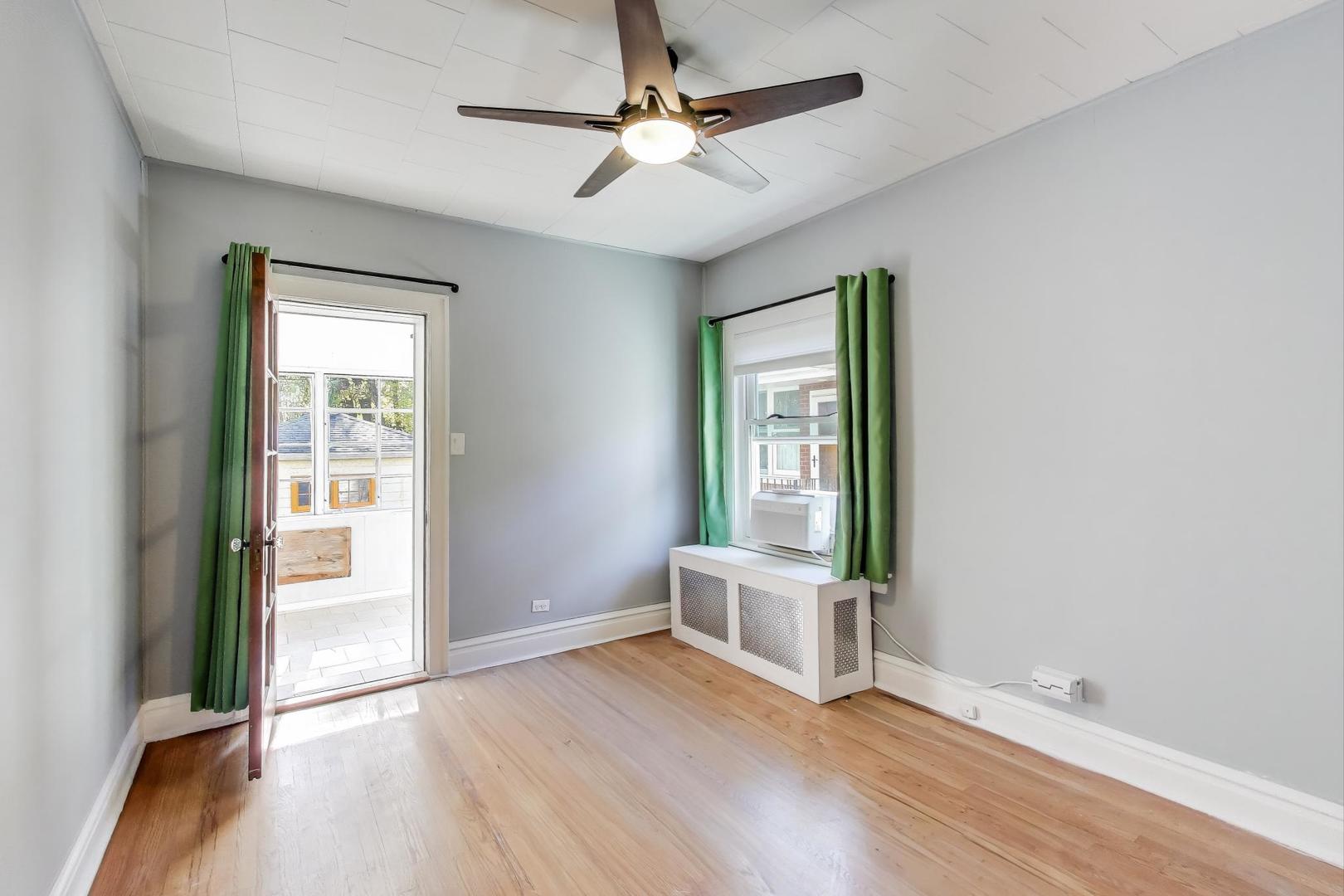 1020 Harvard Terrace Evanston, IL 60202 - Photo 16 of 31 an empty room with wooden floor chandelier fan and windows