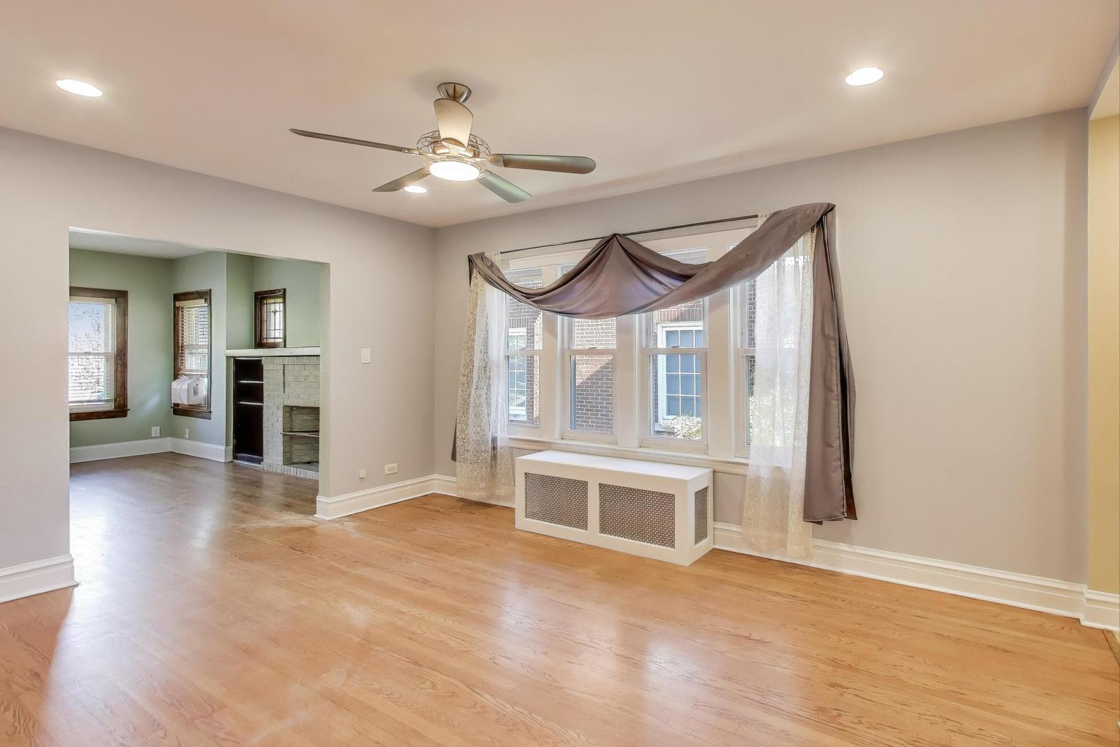 1020 Harvard Terrace Evanston, IL 60202 - Photo 8 of 31 an empty room with wooden floor a ceiling fan and windows