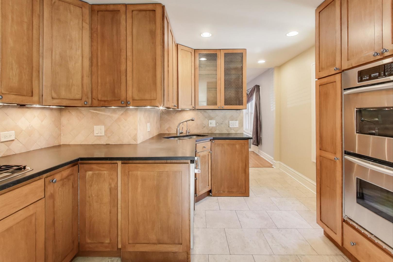 1020 Harvard Terrace Evanston, IL 60202 - Photo 9 of 31 a kitchen with granite countertop wooden cabinets and stainless steel appliances