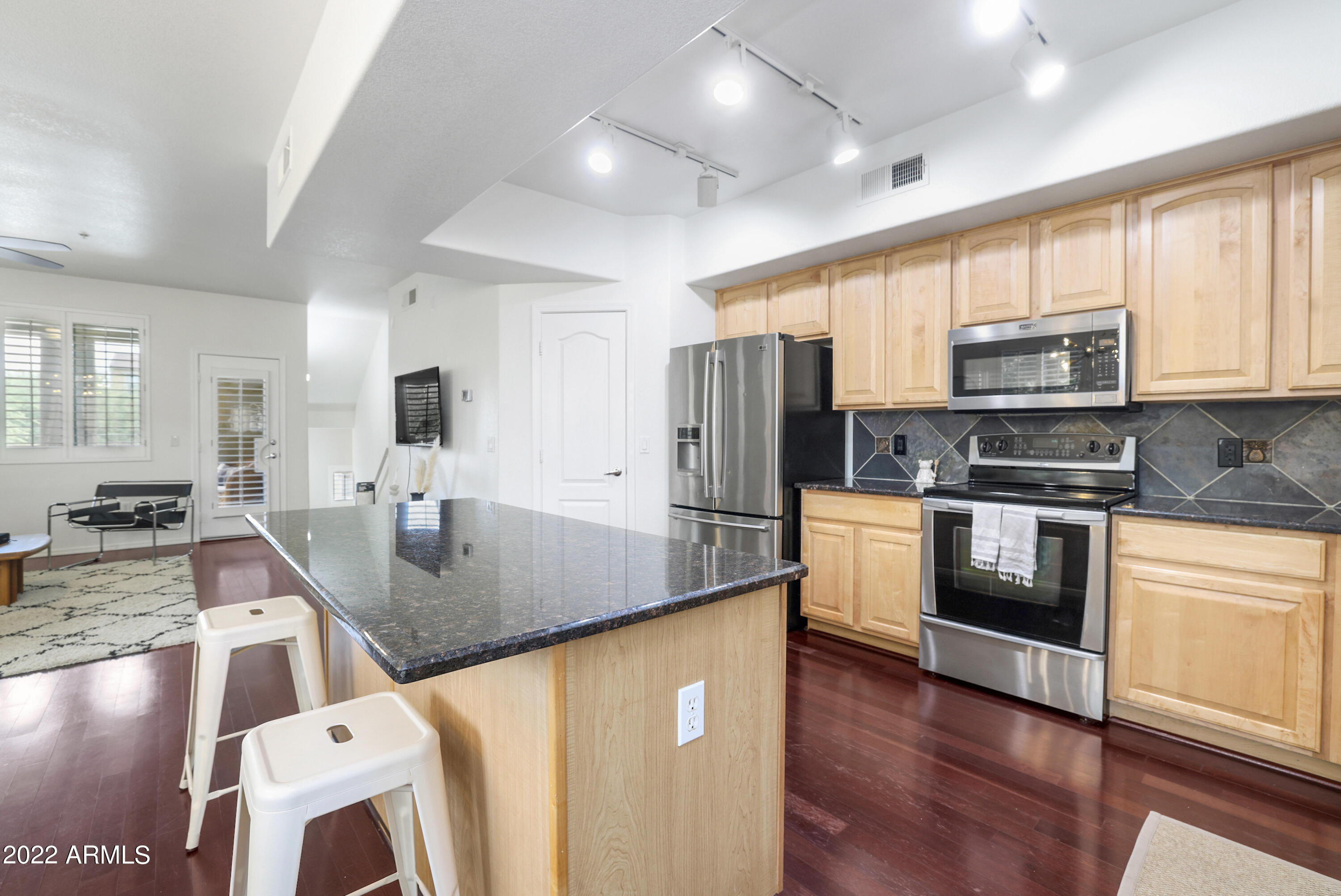 280 South Evergreen Road, Unit 1285 Tempe, AZ 85288 - Photo 9 of 29 a kitchen with stainless steel appliances granite countertop a stove a sink a refrigerator a microwave oven with cabinets and wooden floor