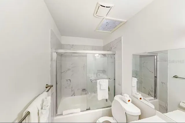 a bathroom with a bathtub shower sink mirror and toilet