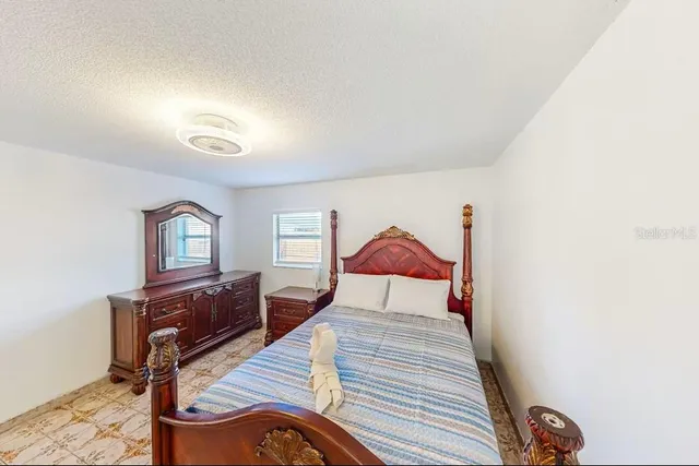 a bedroom with a bed and a dresser with wooden floor