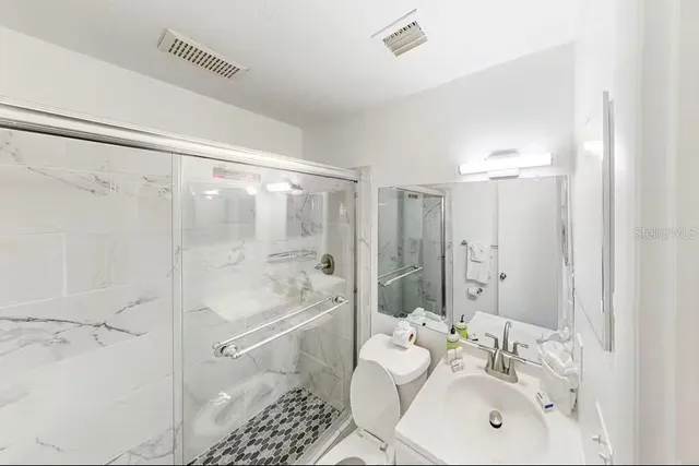 a bathroom with a shower sink and mirror
