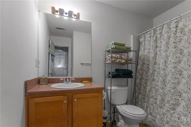 a bathroom with a granite countertop toilet sink and mirror