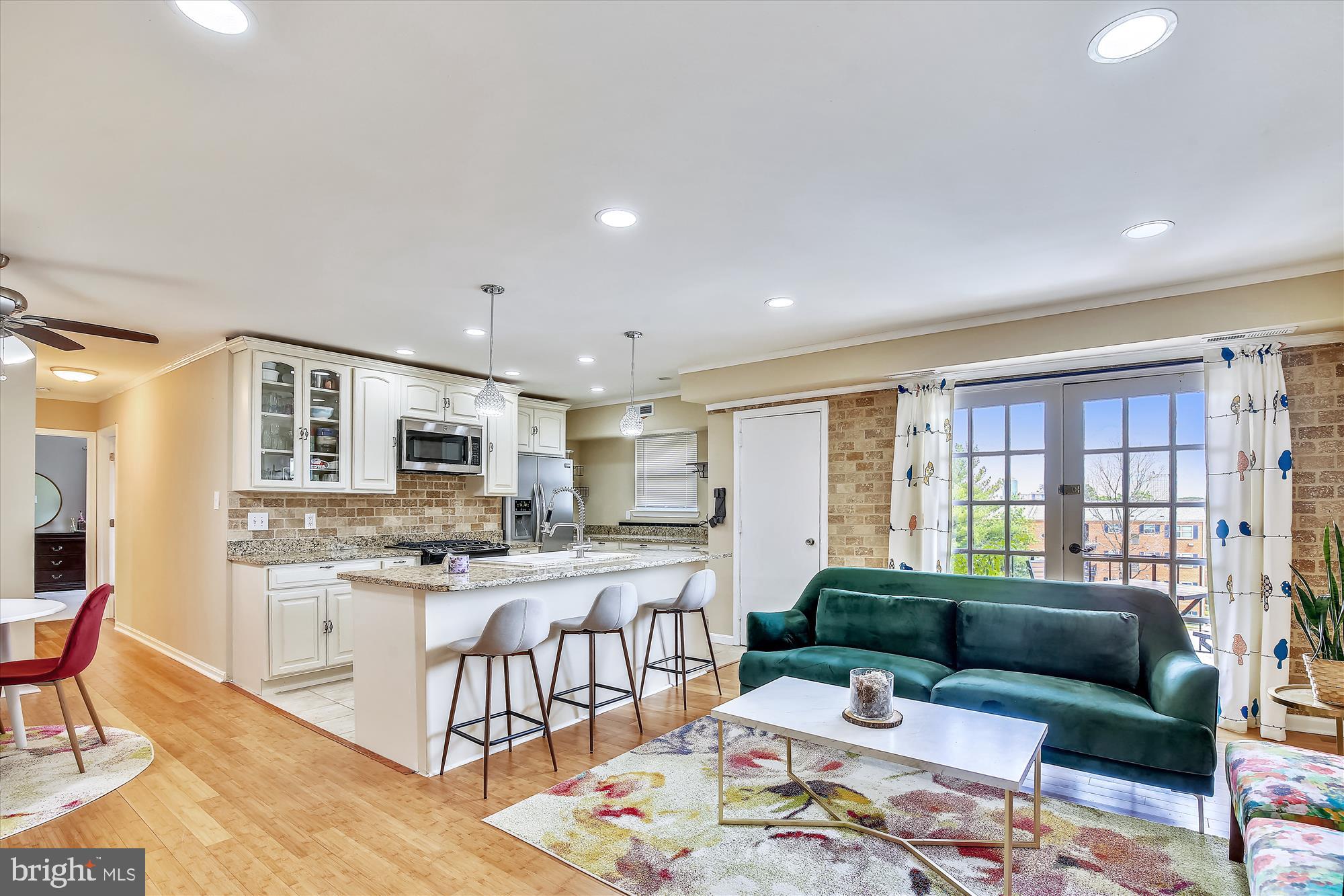 a living room with stainless steel appliances kitchen island granite countertop furniture a rug kitchen view and a window