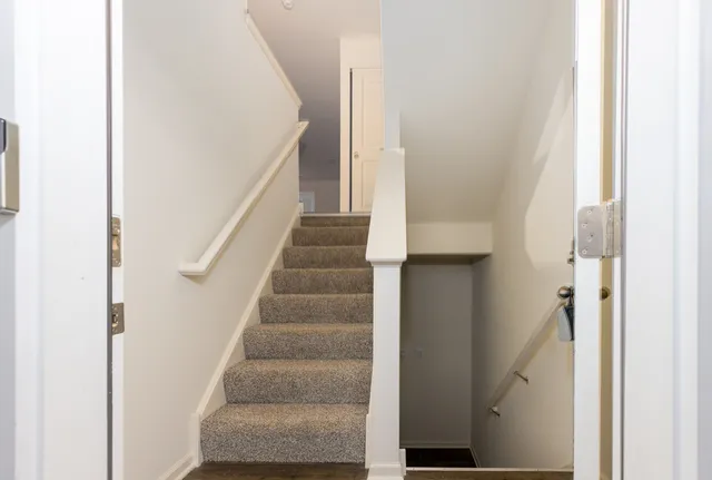 a view of staircase with white walls and white door