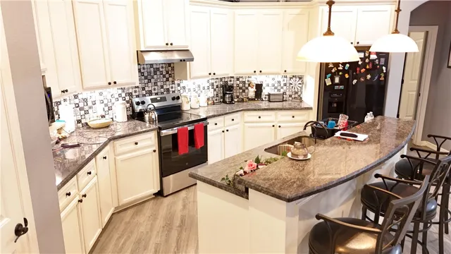 a kitchen with kitchen island granite countertop a sink appliances and cabinets
