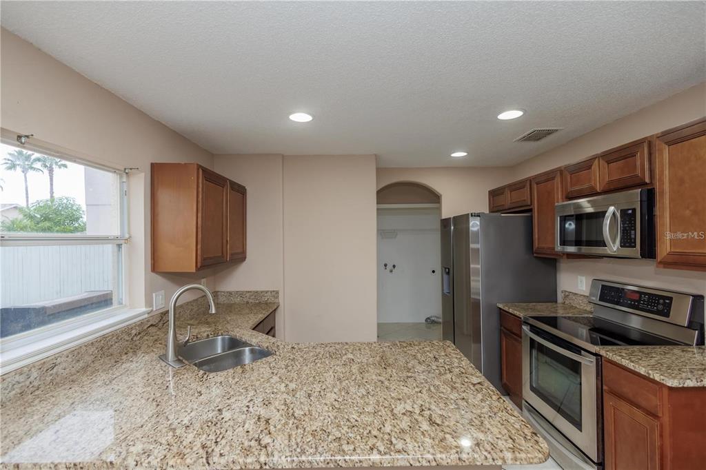 1112 Timberbend Circle Orlando, FL 32824 - Photo 22 of 32 a kitchen with stainless steel appliances granite countertop a stove top oven a sink dishwasher a dining table and chairs with wooden floor