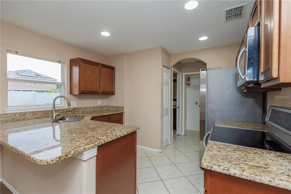 1112 Timberbend Circle Orlando, FL 32824 - Photo 23 of 32 a kitchen with granite countertop a sink a stove and cabinets