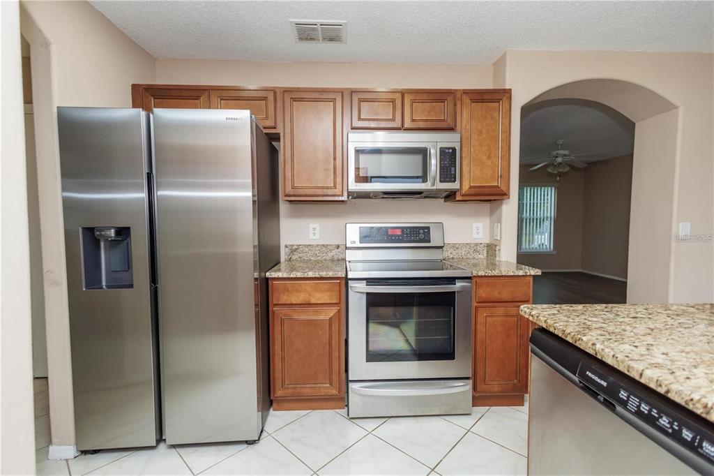 1112 Timberbend Circle Orlando, FL 32824 - Photo 24 of 32 a kitchen with granite countertop a refrigerator and a stove