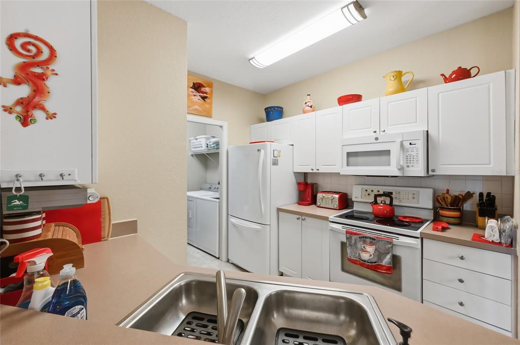 5122 Northridge Road, Unit 210 Sarasota, FL 34238 - Photo 9 of 36 a white kitchen with a refrigerator and cabinets
