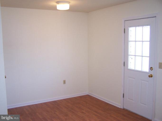 a view of an empty room with wooden floor and windows