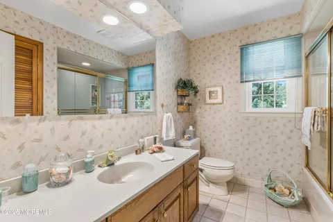a bathroom with a granite countertop toilet a sink and a large mirror