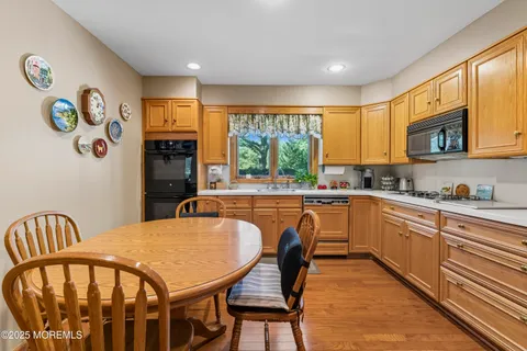 a kitchen with stainless steel appliances granite countertop a stove a sink a refrigerator dining table and chairs with wooden floor