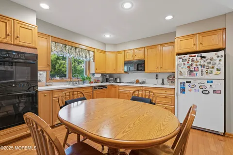 a kitchen with stainless steel appliances granite countertop a stove a sink a dining table and chairs