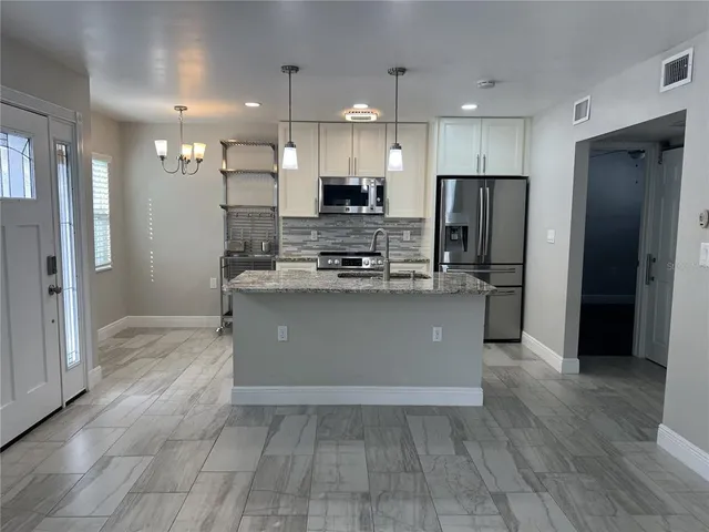 a kitchen with stainless steel appliances granite countertop a refrigerator a sink a stove and a oven