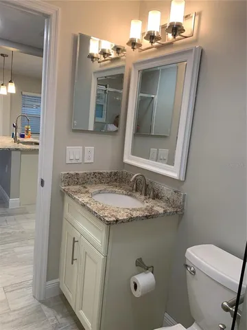 a bathroom with a granite countertop toilet sink and mirror