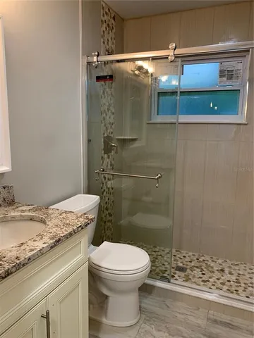 a bathroom with a granite countertop toilet a sink and shower