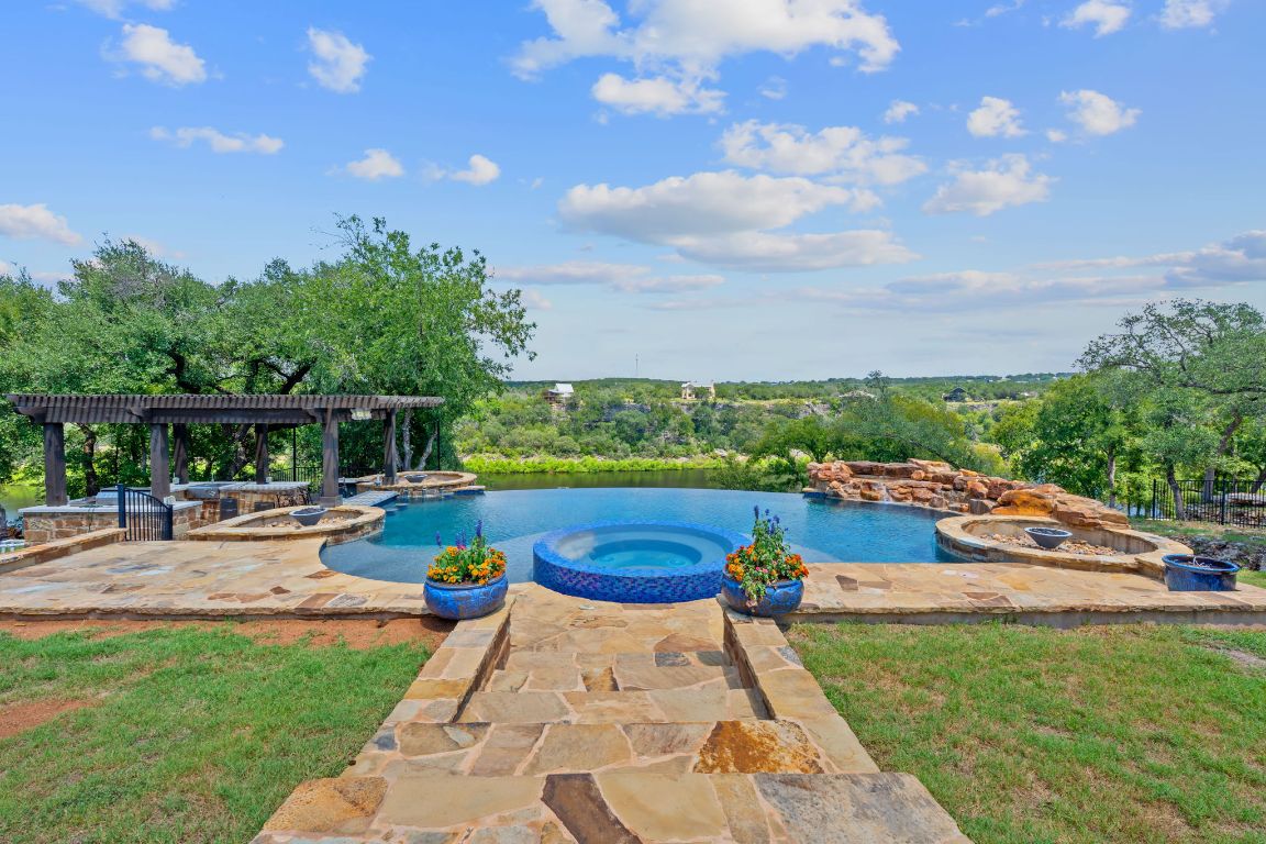 1325 Likeness Road Spicewood, TX 78669 - Photo 26 of 38 View of swimming pool with a patio, a pool with connected hot tub, and three fire pits and outdoor kitchen