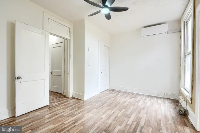 an empty room with wooden floor cabinet and windows
