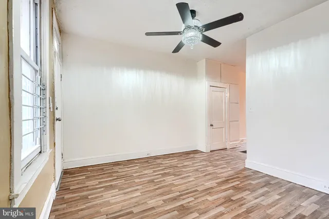 an empty room with wooden floor fan and windows
