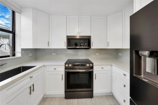 a kitchen with white cabinets and black appliances