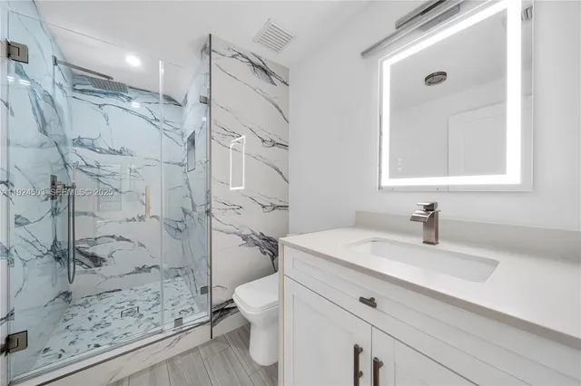 a bathroom with a sink mirror toilet and shower