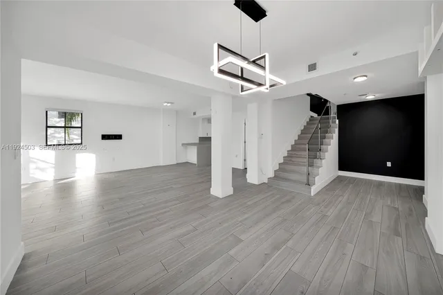 a view of an empty room with wooden floor and a ceiling fan
