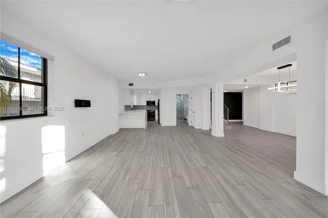a view of a big room with wooden floor and windows