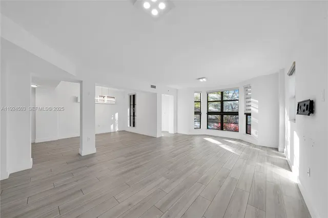 a view of empty room with wooden floor and window