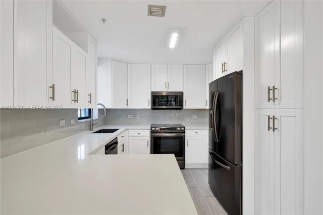 a kitchen with a refrigerator a stove top oven and white cabinets