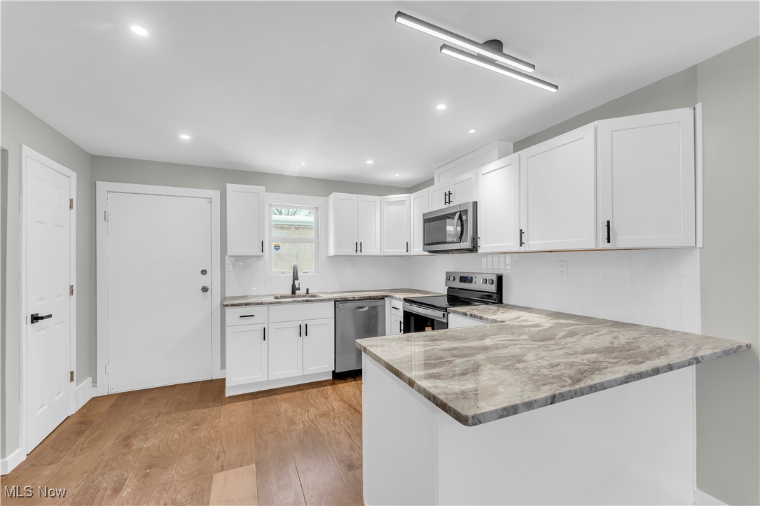 797 Babbitt Road, Unit 15 Euclid, OH 44123 - Photo 7 of 22 Kitchen featuring white cabinetry, stainless steel appliances, light wood finished floors, a peninsula, and recessed lighting