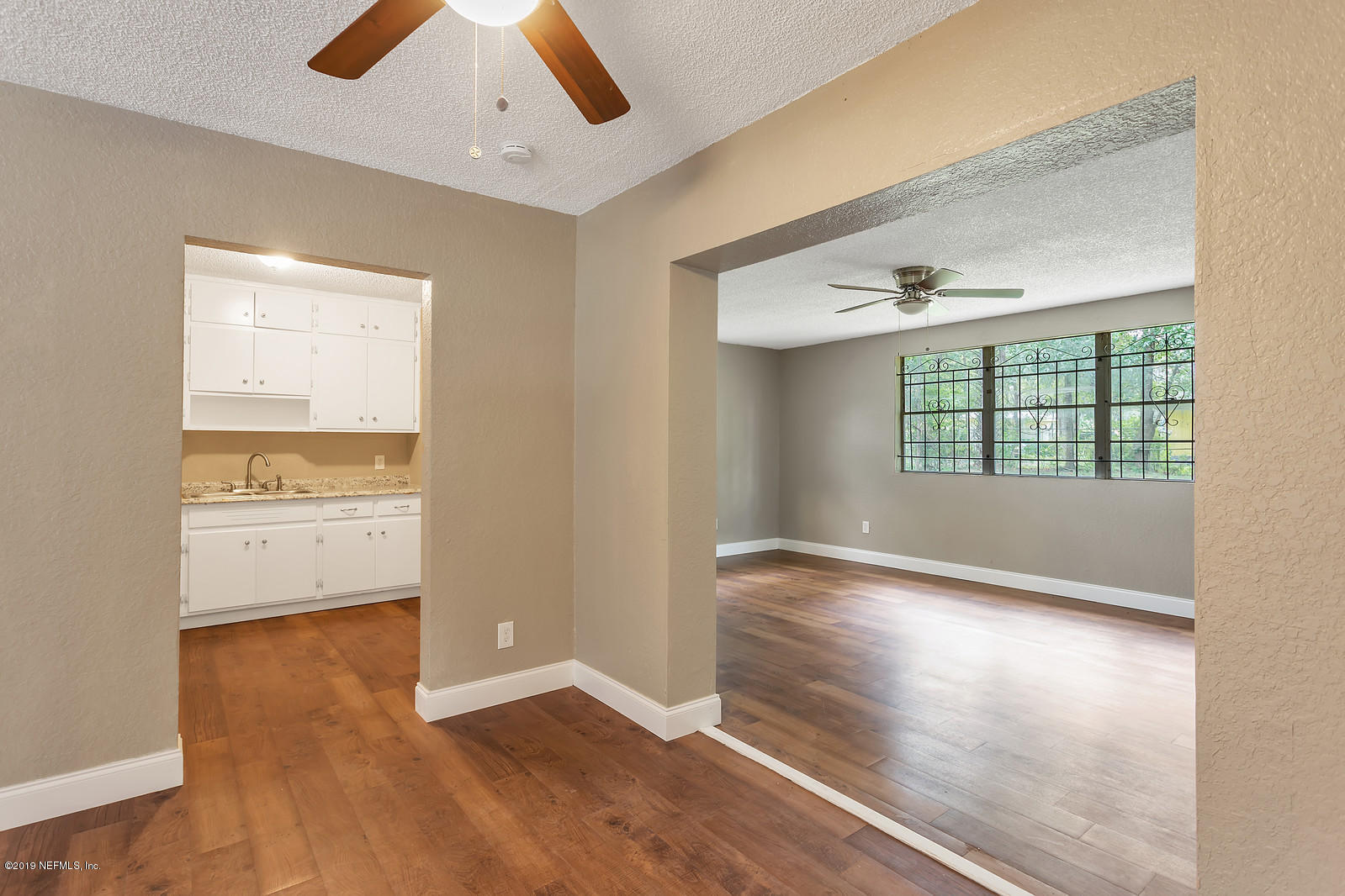 6718 Cavalier Road Jacksonville, FL 32208 - Photo 3 of 15 an empty room with wooden floor cabinet and windows