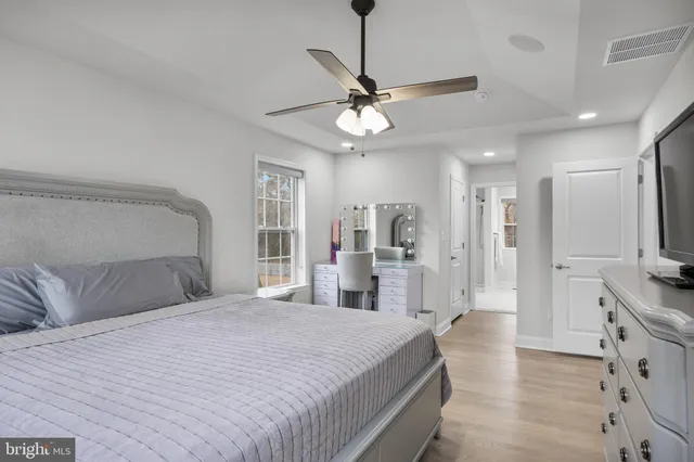 a bedroom with a large bed a flat tv screen and a chandelier