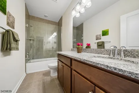 a bathroom with a granite countertop sink a toilet a mirror and shower