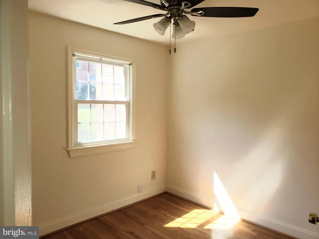 an empty room with a window and a fan
