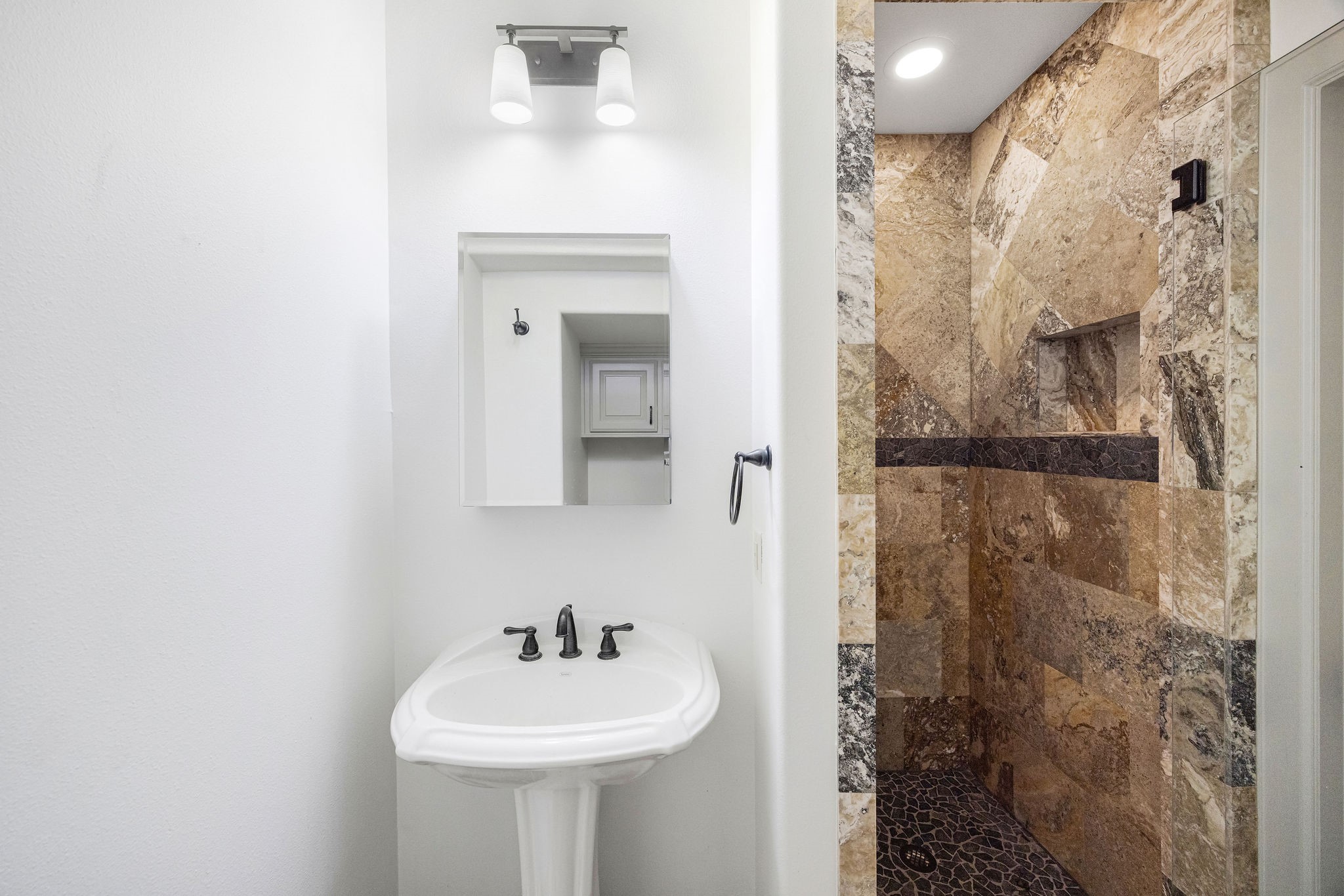 2415 Commonwealth Street Houston, TX 77006 - Photo 11 of 26 The first-floor en suite bath features a beautifully tiled walk-in shower, providing comfort, convenience, and privacy for guests or family.