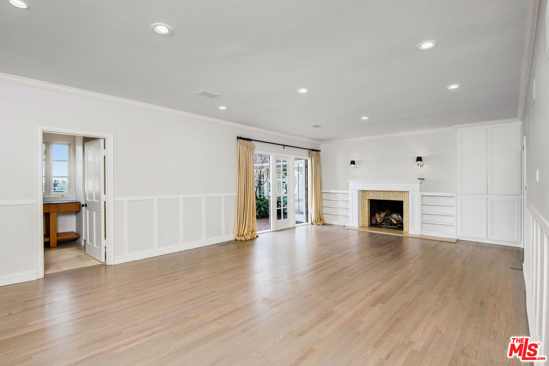 1110 Stradella Road Los Angeles, CA 90077 - Photo 3 of 26 a view of an empty room with wooden floor fireplace and a window