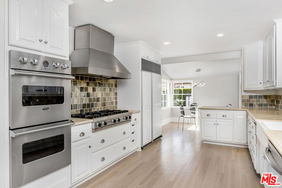 1110 Stradella Road Los Angeles, CA 90077 - Photo 5 of 26 a kitchen with granite countertop a stove top oven a sink dishwasher and a refrigerator with wooden floor