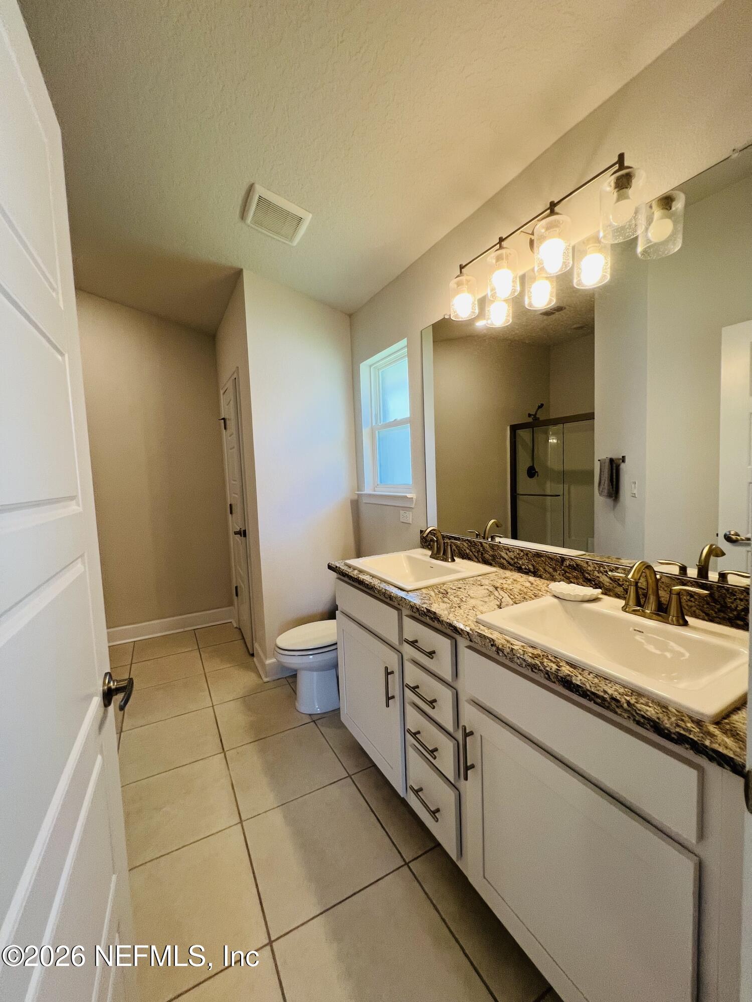 2 Rivertown Road Palm Coast, FL 32137 - Photo 71 of 80 a bathroom with a granite countertop sink a toilet and a mirror