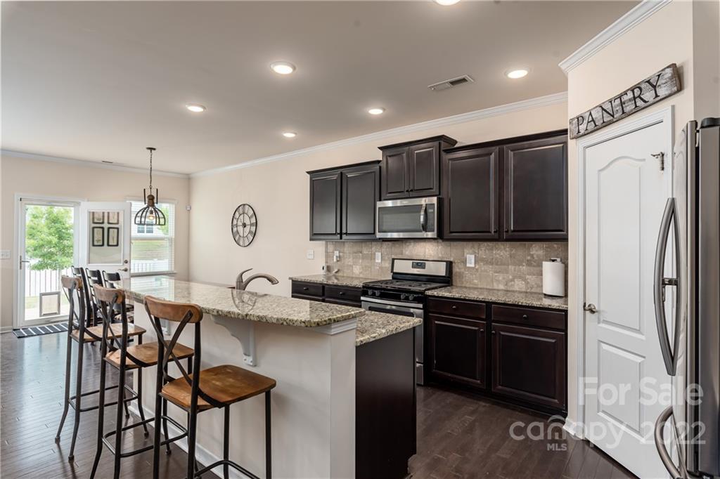 239 Keating Pl Drive Fort Mill, SC 29708 - Photo 7 of 33 a kitchen with stainless steel appliances granite countertop a sink a stove a refrigerator and chairs