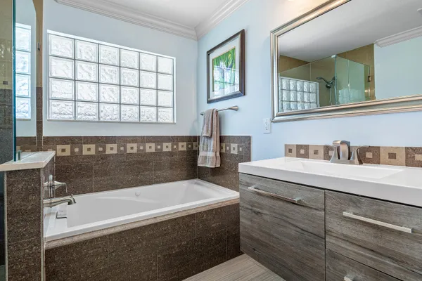 a bathroom with a double vanity sink mirror and bathtub