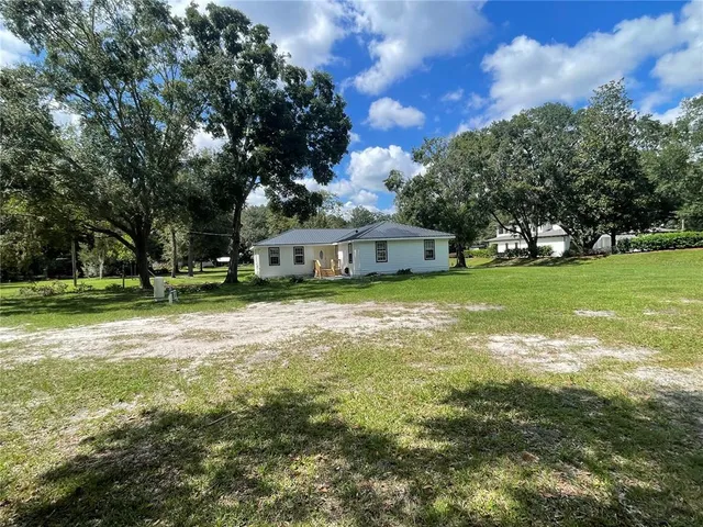a view of a house with a big yard and large trees