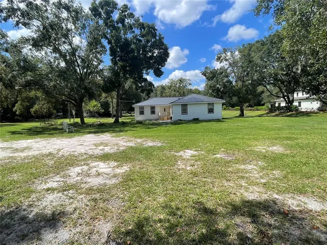 a view of a house with a big yard and large trees