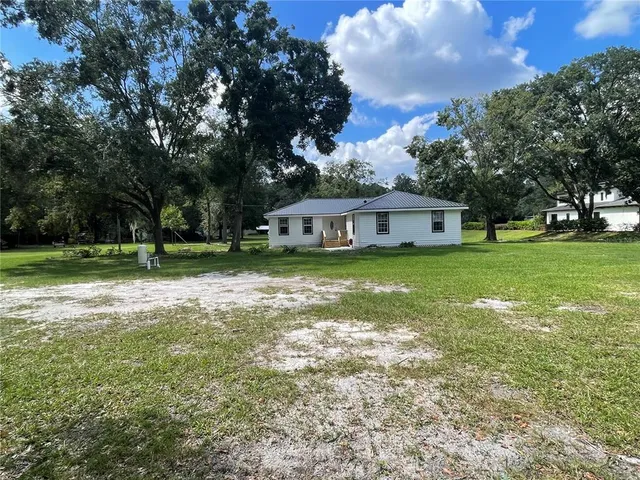 a view of a house with a big yard and large trees