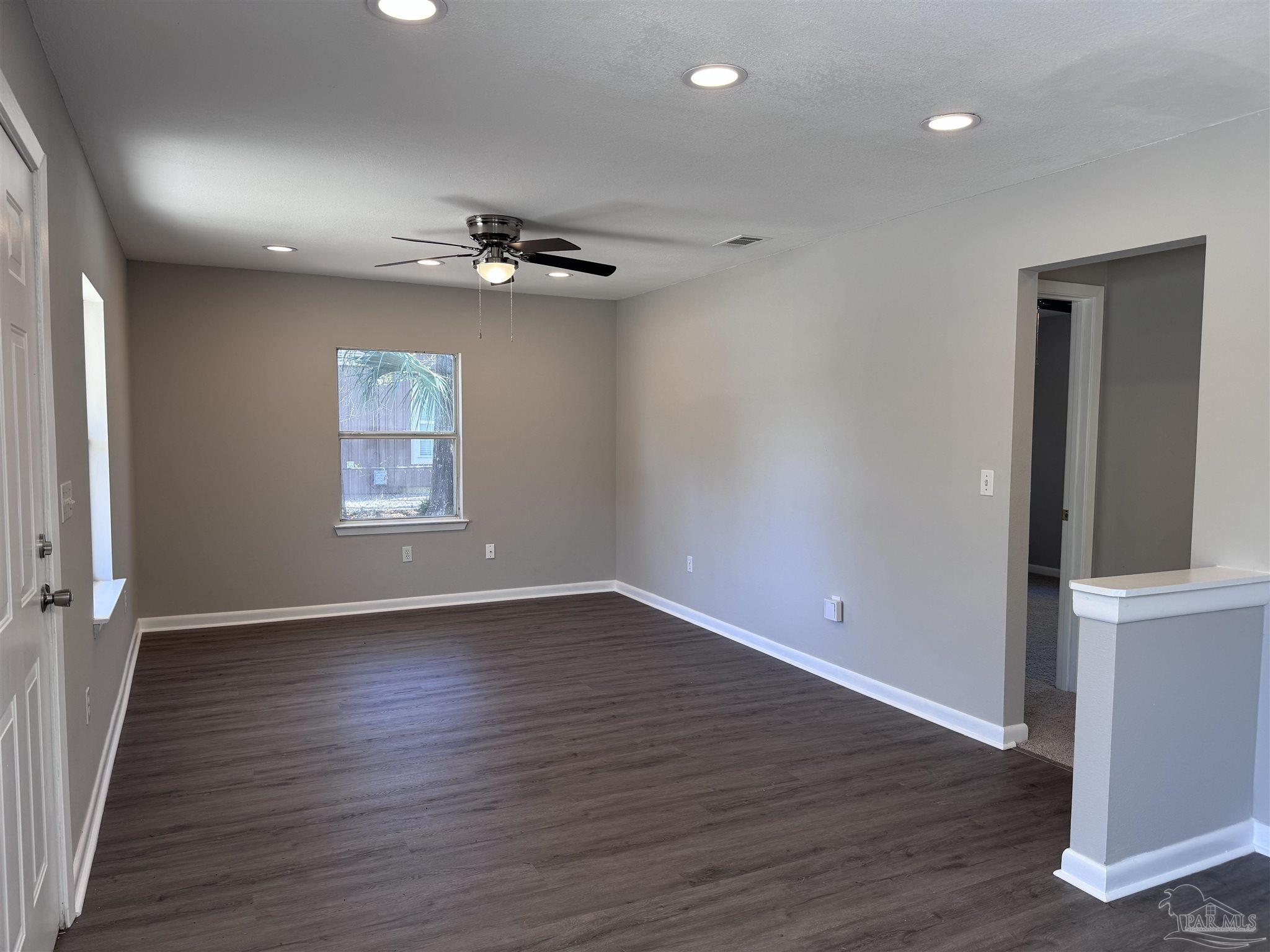 6426 Walnut Street Milton, FL 32570 - Photo 3 of 21 an empty room with wooden floor chandelier and windows