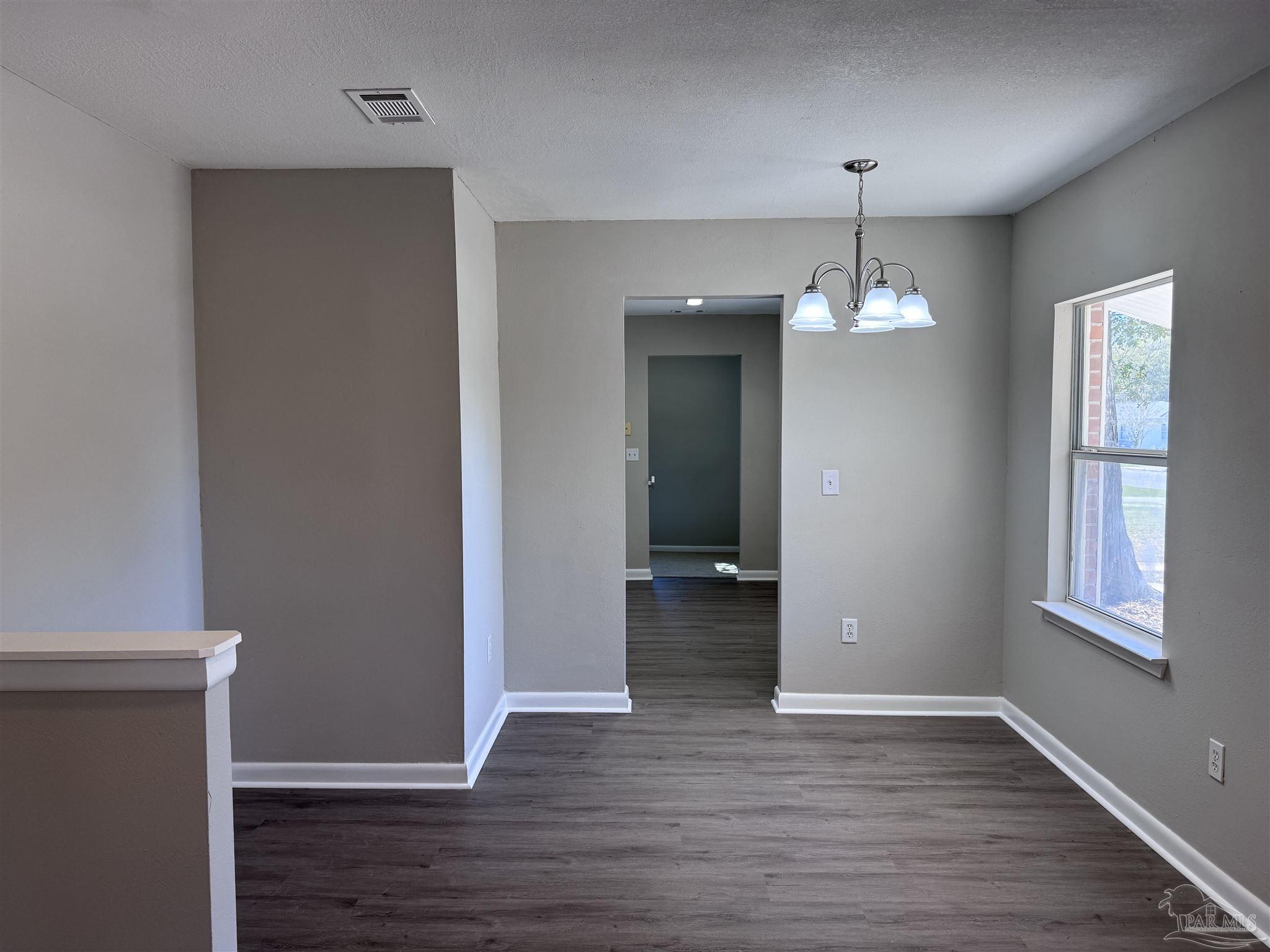6426 Walnut Street Milton, FL 32570 - Photo 4 of 21 an empty room with wooden floor and windows