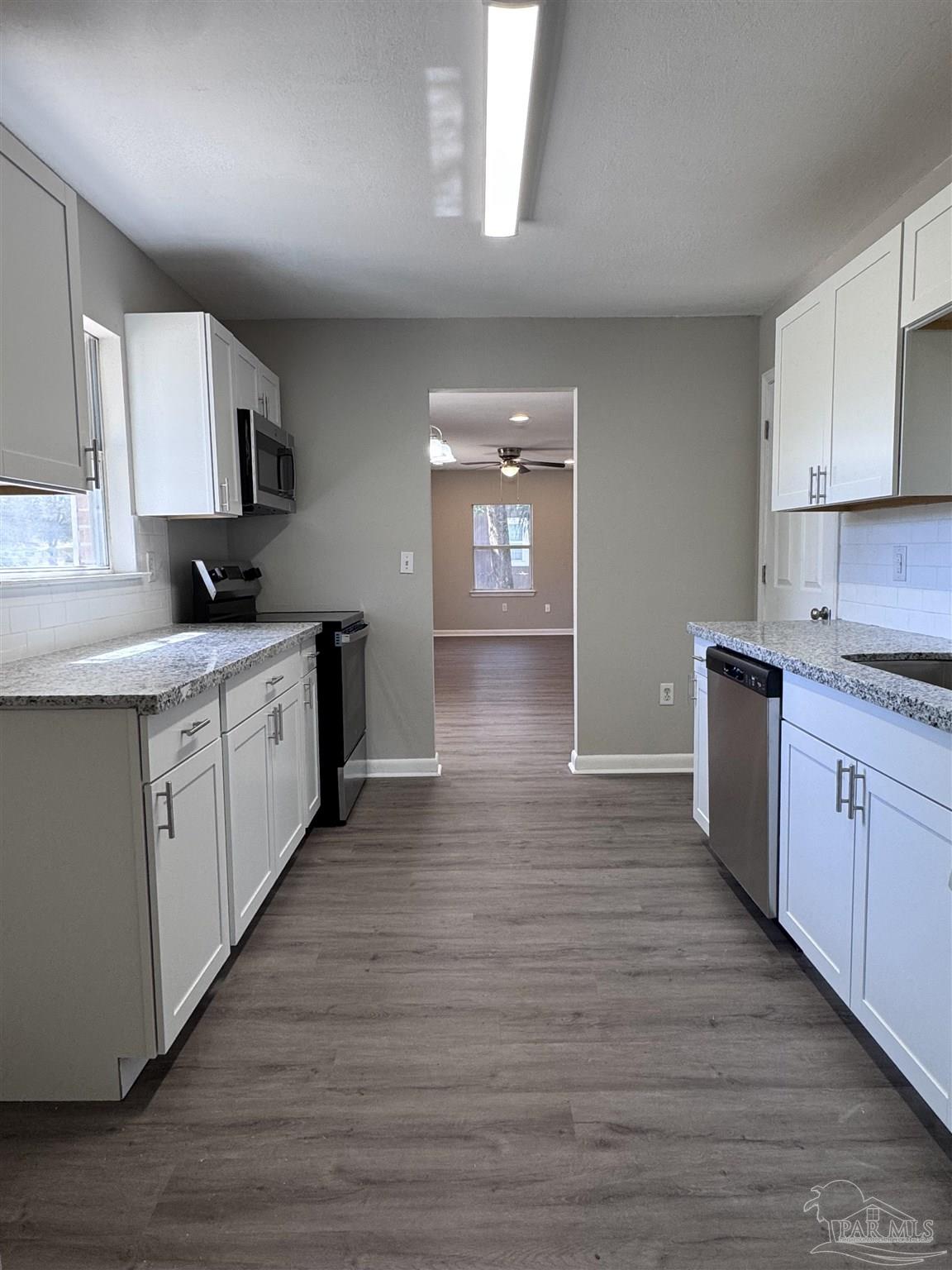 6426 Walnut Street Milton, FL 32570 - Photo 7 of 21 a kitchen with granite countertop a sink cabinets and wooden floor