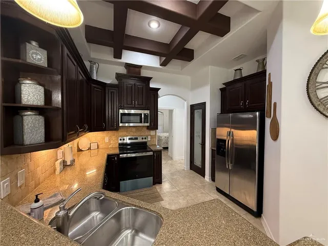 a kitchen with stainless steel appliances granite countertop a refrigerator a stove and a sink with wooden floor